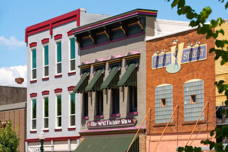A row of multistory, brick buildings in a small U.S. city, with retail uses on the ground floor and apartments above.